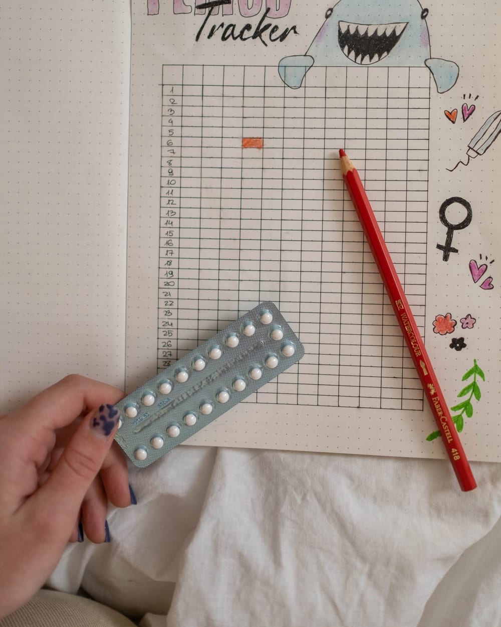 Period tracker notebook with a pill pack and a pencil