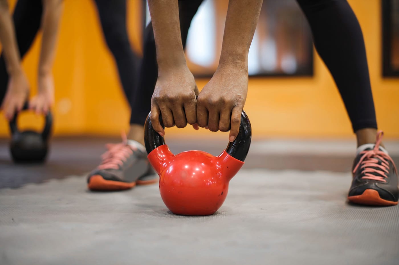 Hands lifting a red kettlebell from the floor