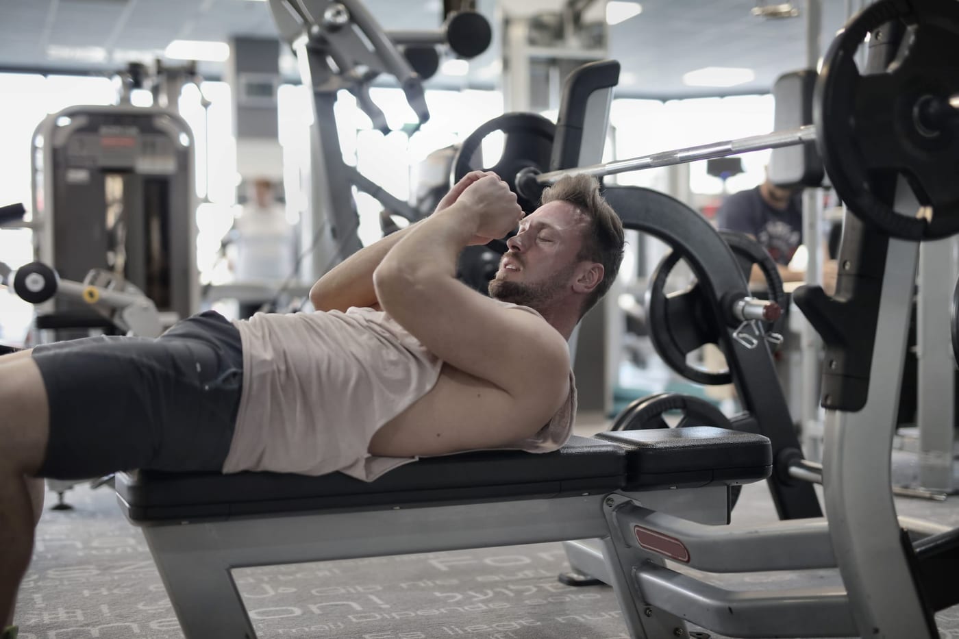 Mann ruht sich nach dem Training auf einer Hantelbank aus