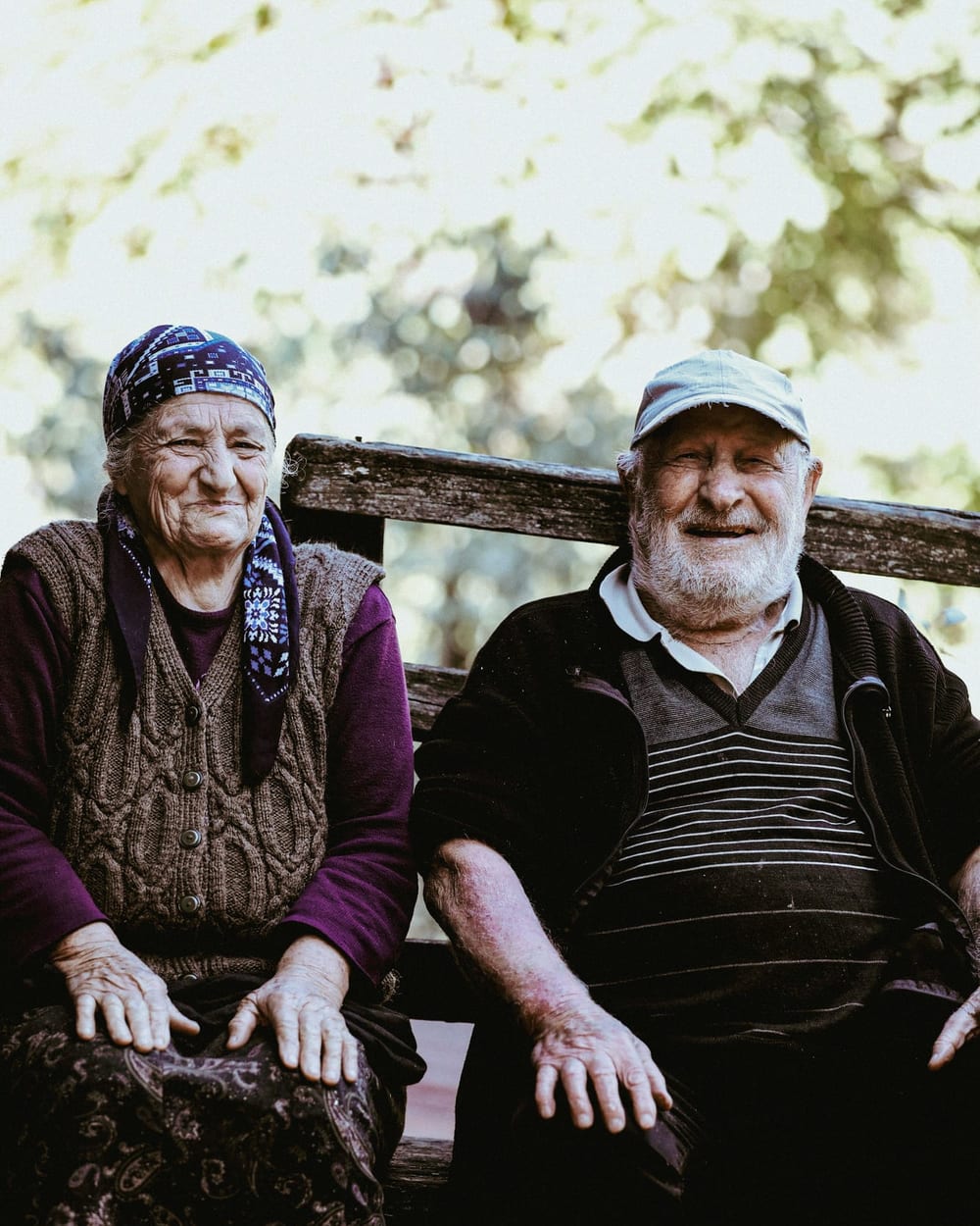 Older couple sitting side by side on a bench outdoors