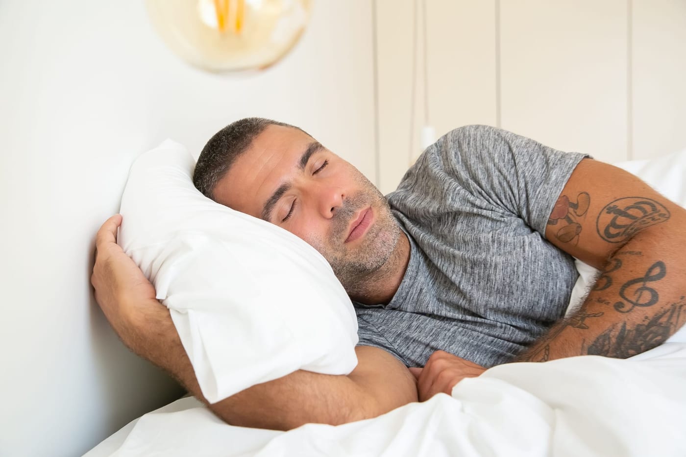 Man sleeping with his arm around a pillow