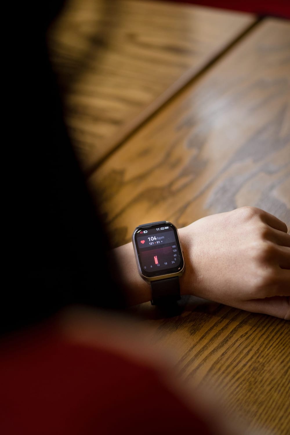 Smartwatch on a wrist resting on a wooden table
