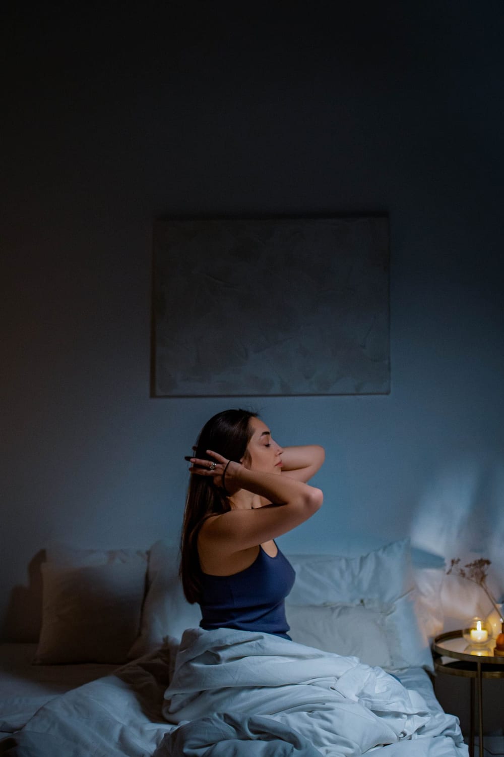 Woman sitting up in bed stretching her neck