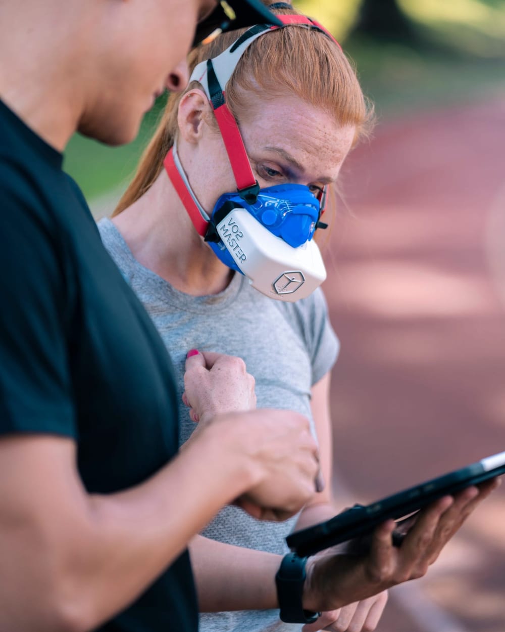 Woman wearing a fitness test mask while a trainer checks results
