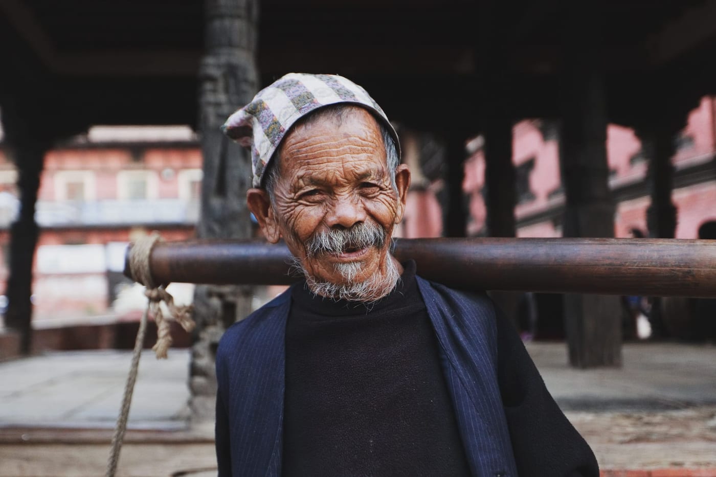 Smiling older man carrying a pole across his shoulders